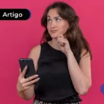 Pessoa de cabelo castanho escuro com expressão de dúvida, segurando um celular.