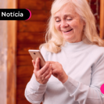 Pessoa de mais idade mexendo no celular e sorrindo.