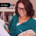 Pessoa sorrindo segurando um papel e uma caneta