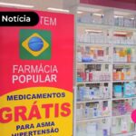 Foto de uma farmácia com adesivo na vitrine informando "Aqui tem Farmácia Popular, Medicamentos Grátis"