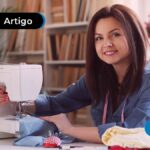 Pessoa sorrindo costurando em uma máquina de costura