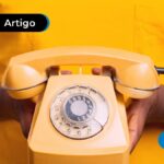 Pessoa segurando um telefone de disco laranja