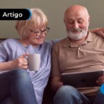 Duas pessoas de mais idade sorrindo, olhando para um tablet