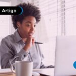 Pessoa surpresa olhando para o computador, segurando uma caneta