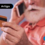 Pessoa de mais idade com o celular no ouvido olhando para um cartão