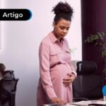 Pessoa olhando para os papéis em cima da mesa, com a mão na barriga