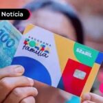 imagem de pessoa segurando cartão do bolsa familia e notas de 100 reais