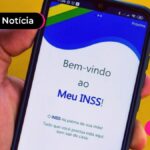 Mão segurando celular com aplicativo do Meu INSS.