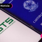 Celular com aplicativo do FGTS na tela e carteira de trabalho ao lado.