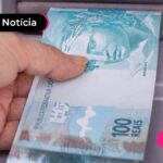 Mão segurando nota de cem reais.