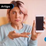 Pessoa com olhar de dúvida apontando para um celular