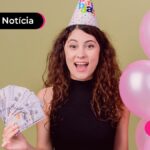 Jovem sorrindo com chapéu de aniversário e balões rosa ao lado.