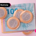 Notas de cem reais e moedas de um real espalhadas.