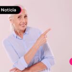 Pessoa de idade sorrindo apontando para o lado.