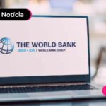 Computador com ilustração de site "Banco Mundial" na tela.
