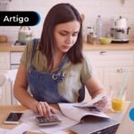 Jovem sentada com vários papéis espalhados pela mesa e uma calculadora.