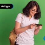 Jovem sorrindo com mochila marrom nas costas e segurando celular.