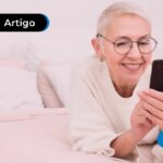 Pessoa de idade sorrindo e segurando celular.