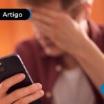 Pessoa com a mão na cabeça e expressão preocupada segurando celular.