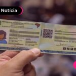 Mão segurando documento de identificação novo.
