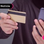 Pessoa segurando cartão dourado e celular.