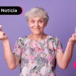 Pessoa de idade sorrindo fazendo sinal de dinheiro com as mãos.