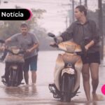 imagem de pessoas empurrando moto em lugar alagado