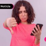 Jovem com expressão triste segurando celula.