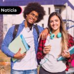 Estudantes sorrindo segurando cadernos.