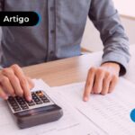 Pessoa mexendo em uma calculadora e vendo um papel