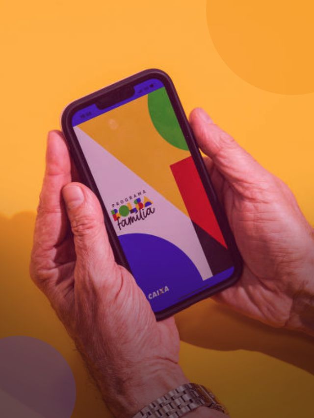 Mão segurando celular com aplicativo do programa Bolsa Família na tela.