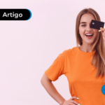 Jovem sorrindo e segurando cartão de crédito para pagar contas.