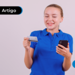 Pessoa sorrindo segurando um cartão e um celular