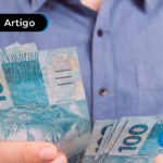 Pessoa segurando notas de cem reais