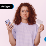 Pessoa com olhar confuso segurando um celular e um cartão de crédito