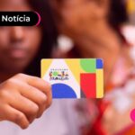 Pessoa segurando cartão do Bolsa Família e recebendo o pagamento do mês de setembro.