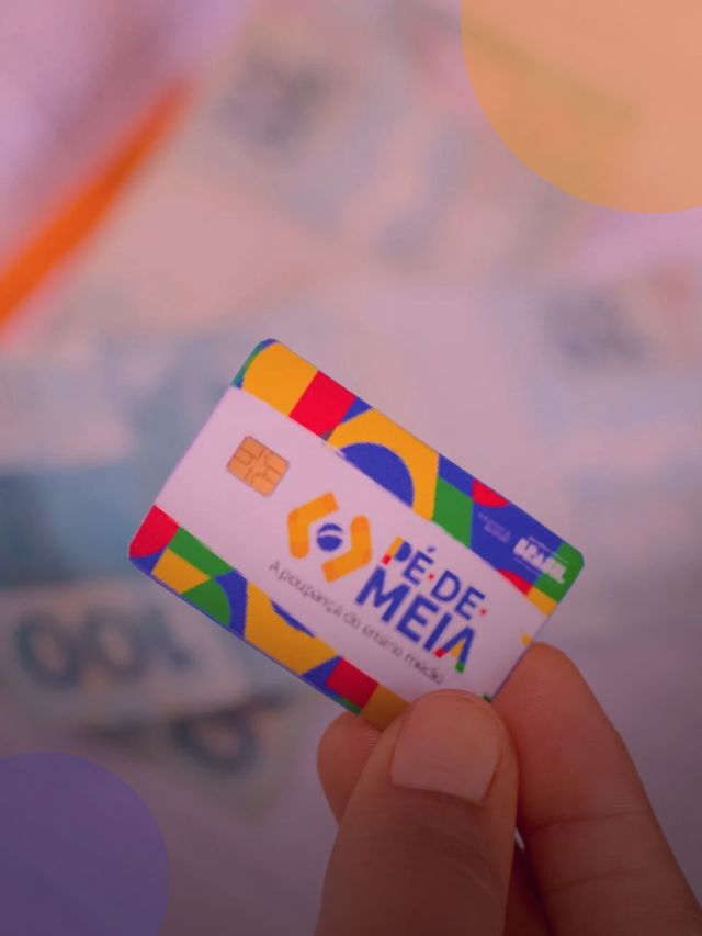 Pessoa segurando cartão do programa Pé-de-Meia e notas de cem reais no fundo.