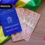 Carteira de trabalho e notas de cinquenta reais ao lado.