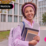 Pessoa sorrindo segurando livros e uma mochila