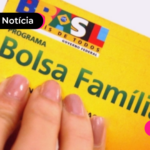 Mão segurando cartão amarelo do programa Bolsa Família.