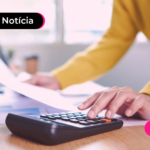 Pessoa segurando papéis e usando calculadora.