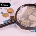 Moedas espalhadas em mesa com lupa ao lado.