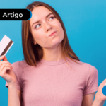 Pessoa com olhar de dúvida segurando um cartão e um celular