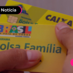 Mão segurando cartão amarelo do Bolsa Família.