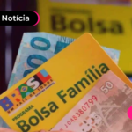 Mão segurando cartão amarelo do programa Bolsa Família e notas de cem reais.