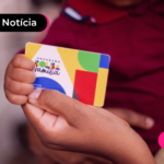 Mão segurando cartão colorido do programa Bolsa Família.