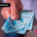 Mão segurando nota de cem reais.