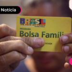 Pessoa segurando cartão amarelo do programa Bolsa Família.