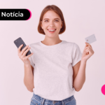 Pessoa sorrindo enquanto segura celular e cartão.
