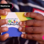 Mão segurando cartão colorido do programa Bolsa Família.